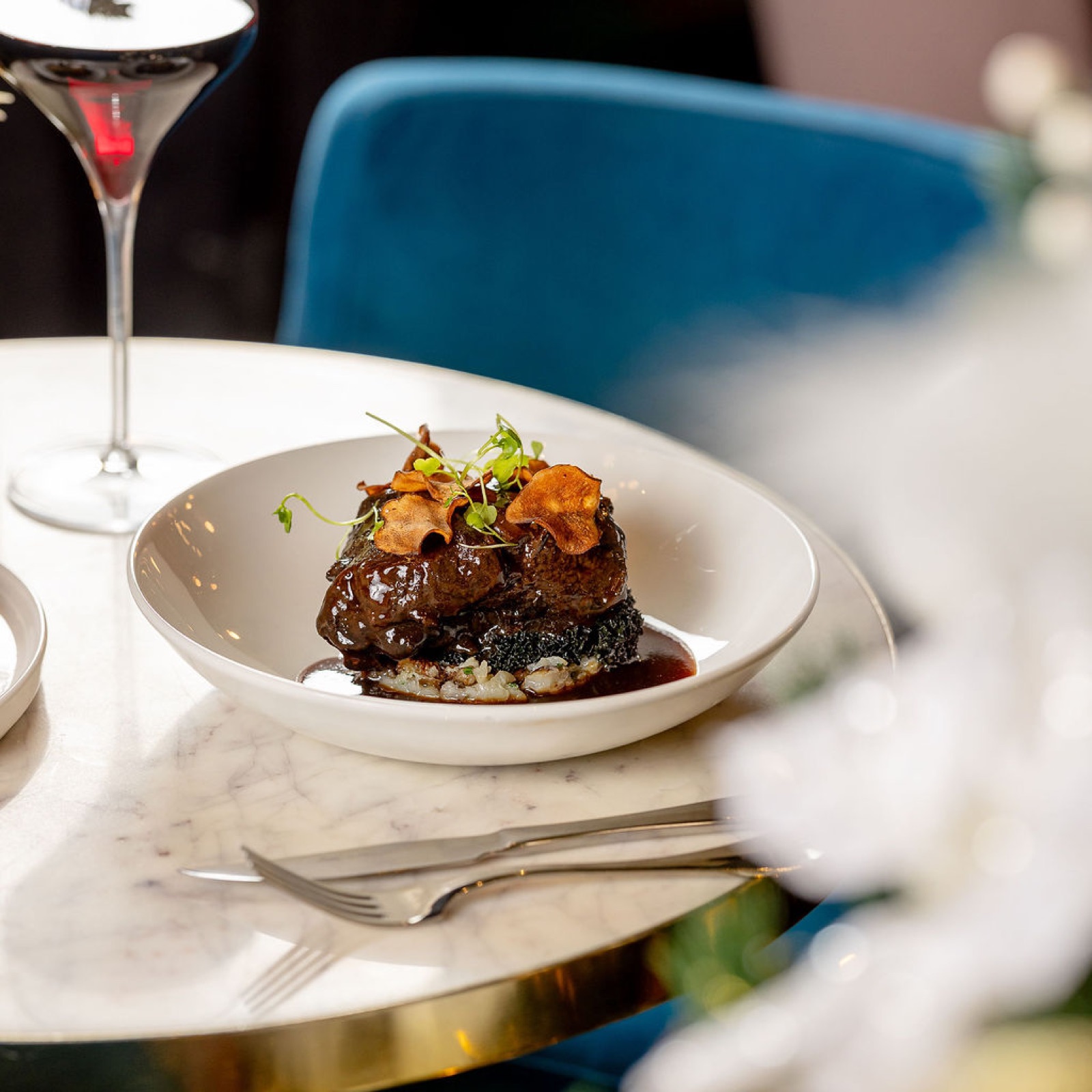 Red wine braised beef cheek with a glass of red, festive bokeh behind