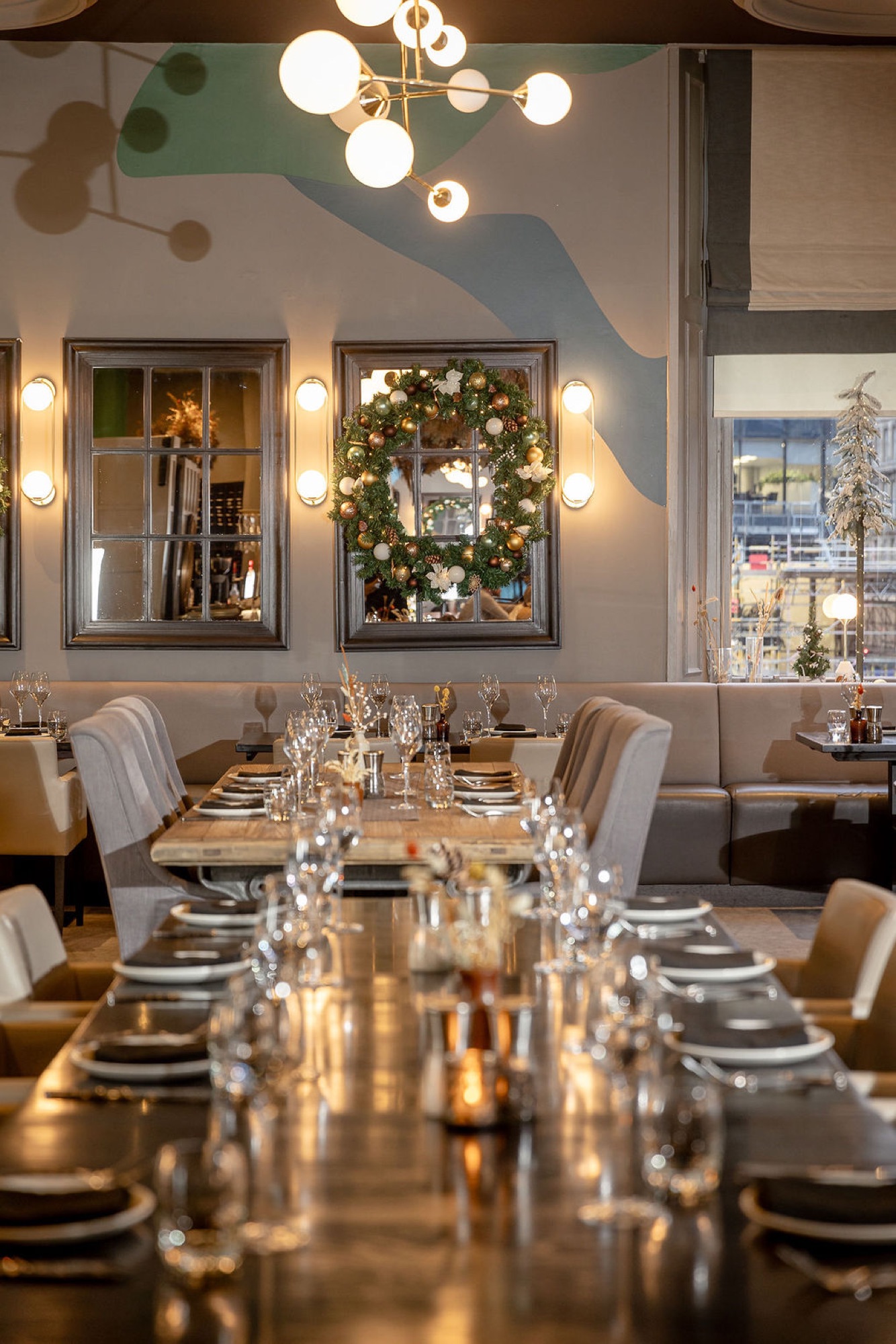 A long table at Glaschu dressed for a festive dinner, a Christmas wreath on the mirror behind