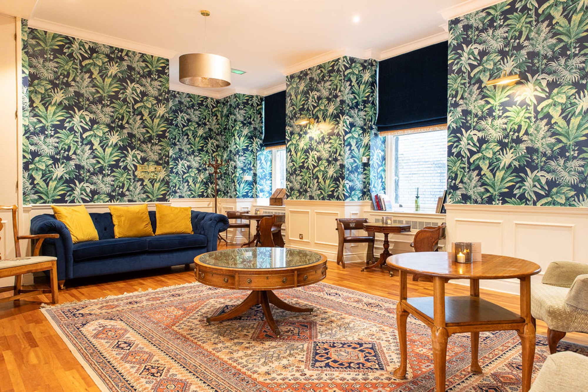 Kelvin Room at Glaschu: botanical wallpaper, a navy chesterfield and antique tables