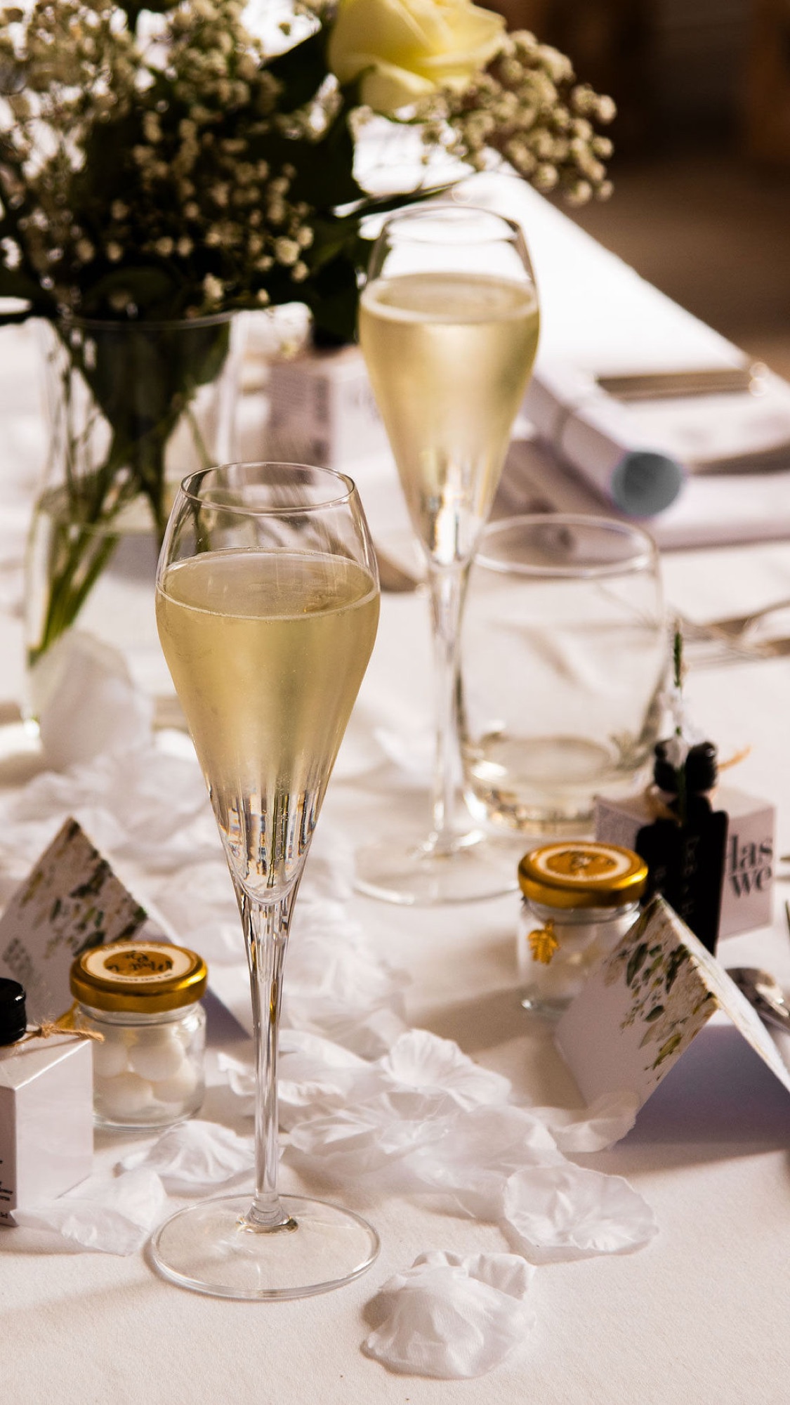 Champagne flutes and petals on a dressed wedding table at Glaschu